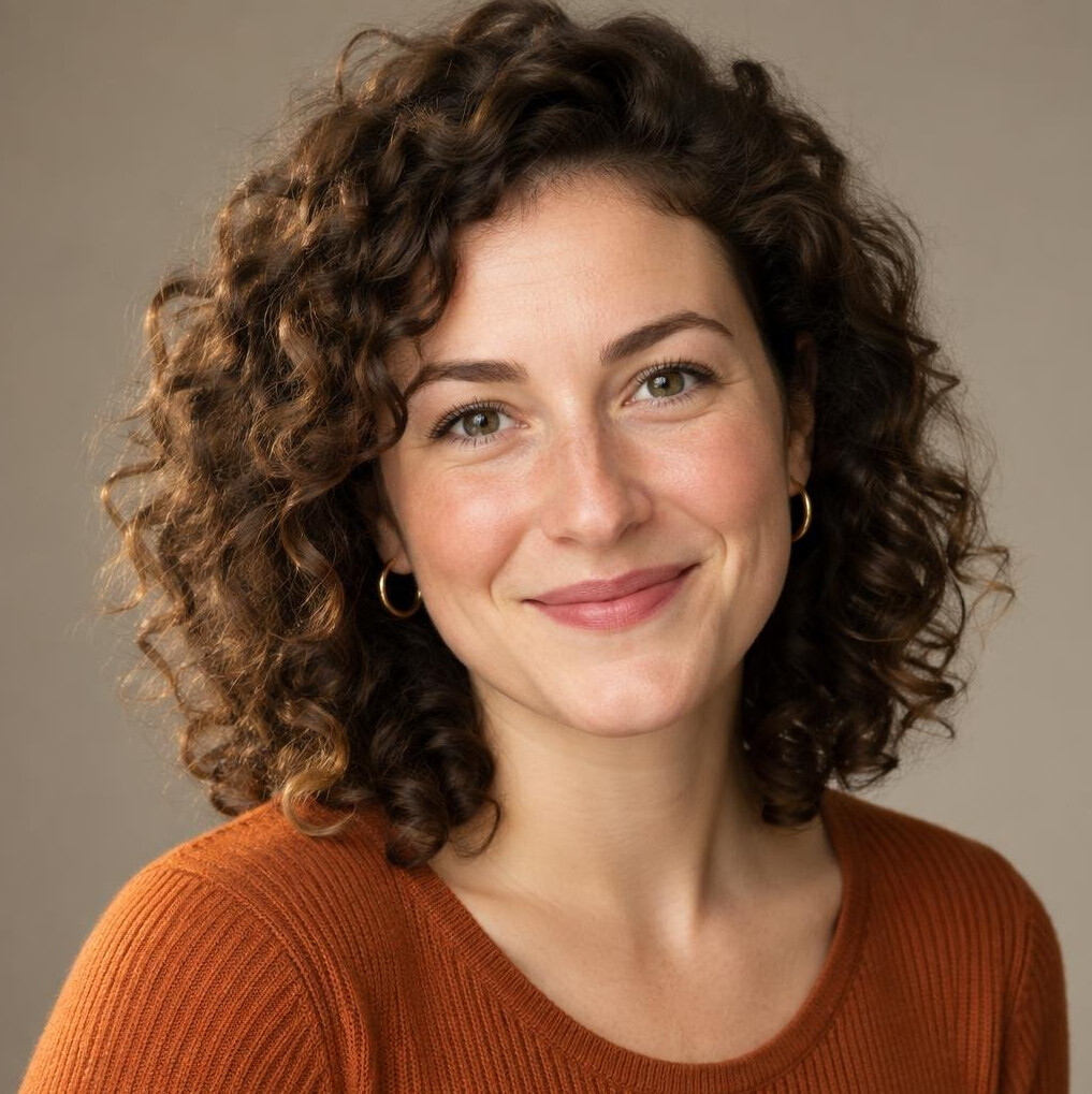 Studio portrait of a woman with curly hair wearing a warm-toned top